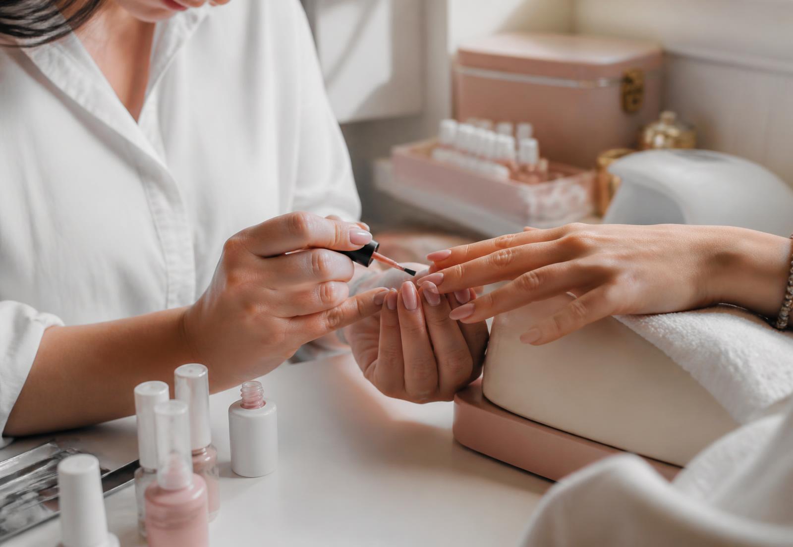 Kosmetyczka nakładająca lakier hybrydowy podczas manicure w gabinecie MS Beauty